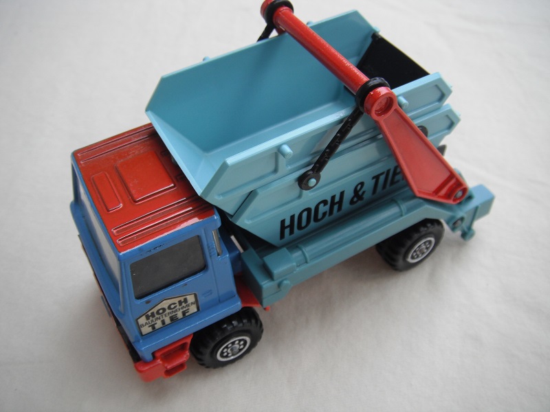 11. Blue &amp; red cab/type 2 cab roof/very light blue skip/red base/Hock &amp; Tief label on cab door/small steering wheel.