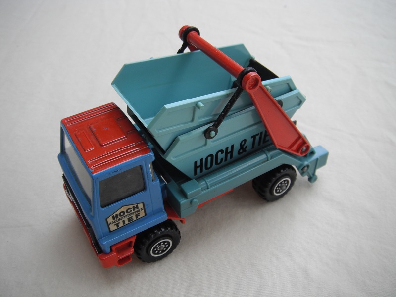 10. Blue &amp; red cab/type 2 cab roof/light blue skip/light red base/Hock &amp; Tief label on cab door/small steering wheel.