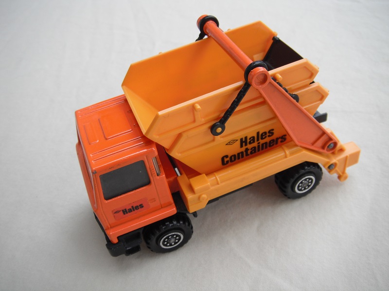 6.  Orange cab/type 2 cab roof/dark yellow skip/black base/hales label on cab door/small steering wheel.