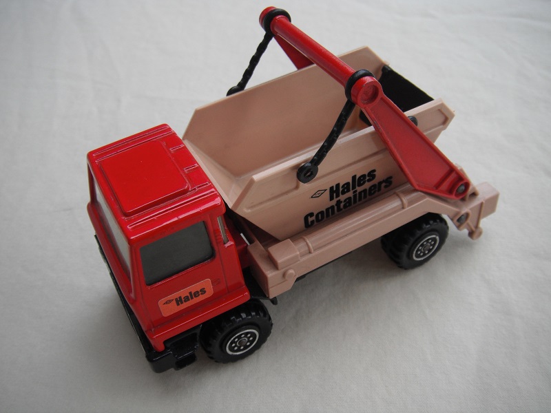 3.  Red cab/type 1 cab roof/tan skip/black base/Hales label on cab door/large steering wheel.