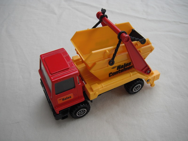 1.  Dark red cab/type 1 cab roof/yel skip/black base/Hales label on cab door/small steering wheel.