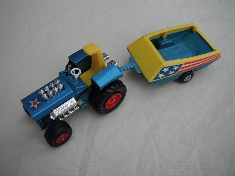 12. Metallic blue body w/star label/dark yellow seat/dark yellow radiator &amp; gas pedal/metallic blue &amp; yellow trailer/blue stars &amp; red stripes label/Maltese cross wheels.