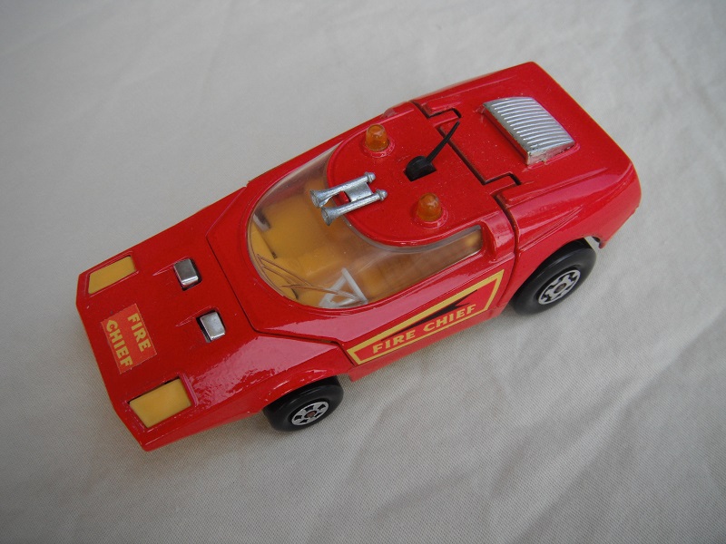 6. Bright red body/yellow base/amber dome lights/clear window/orange-yellow interior/black antenna/Fire Chief labels.