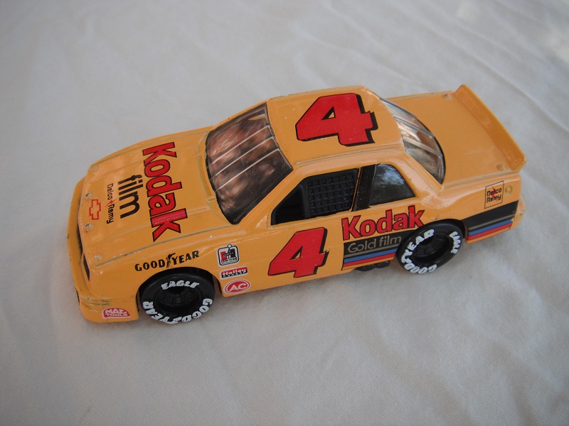 4. Dark yellow body w/various racing logos/black China base/gray interior/clear windows/Goodyear in white on wheels/&quot;Kodak&quot; &amp; &quot;4&quot;.
