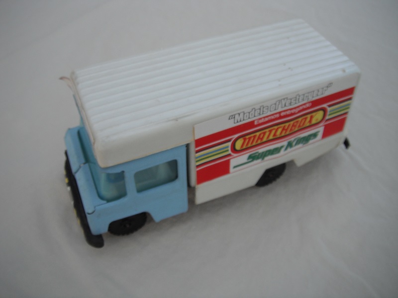 2. Light blue cab/white plastic body/metal base/black plastic wheels/light blue windows/cream interior/blue steering wheel/labels w/various adverts of Matchbox ranges.