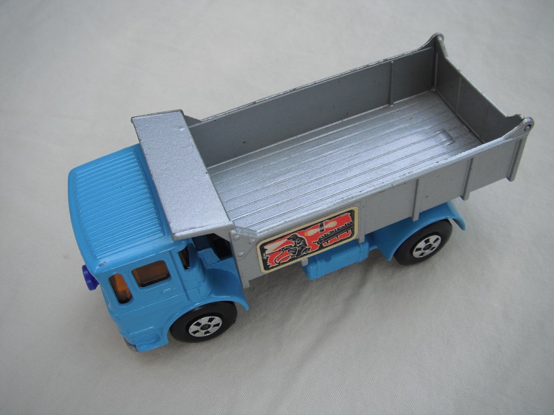 22. Lt.blue cab/silver tipper/silver base/cast block/5 spk whls/blk xle cvr f.fwd/amb wind/blue plastic front &amp; blue on base/miner on lt.yel lbl/in #3 tailgate.