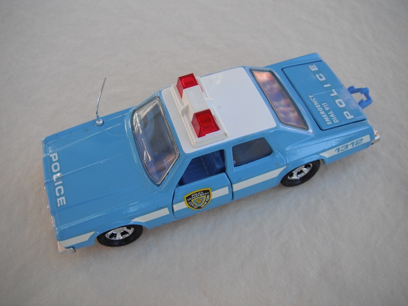 10. Lt. blue body/white roof/black England base/blue interior/clear windows/no trim/red dome lights/white frame/NYC Police decals.