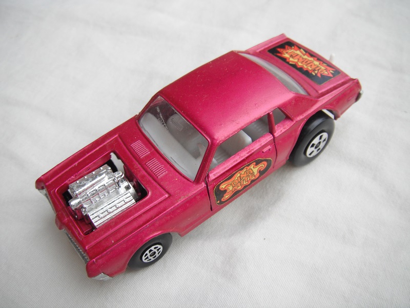 9. Purple body/unpainted England base/clear windows/spiro &amp; five spoke wheels/&quot;Dinamite&quot; label with red &amp; yellow outline.