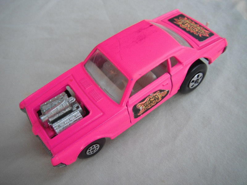 6. Dk. pink body/unpainted England base/clear windows/spiro &amp; five spoke wheels/&quot;Dinamite&quot; label letters in orange.