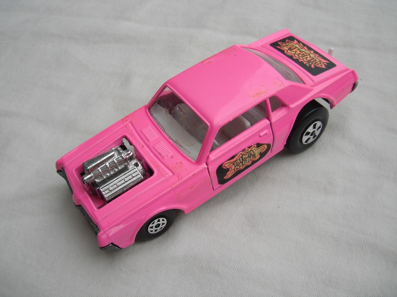 5. Pink body/unpainted England base/clear windows/spiro &amp; five spoke wheels/&quot;Dinamite&quot; label letters in orange.