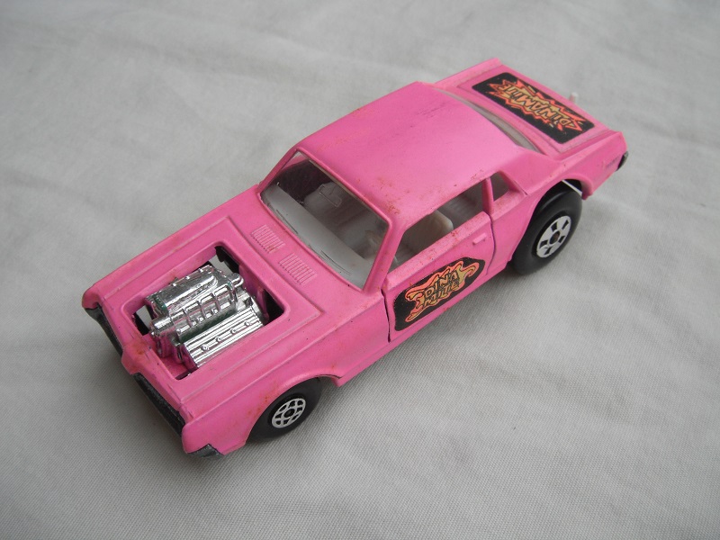 1. Lt.pink body/unpainted England base/clear windows/spiro &amp; five spoke wheels/&quot;Dinamite&quot; label letters in orange.