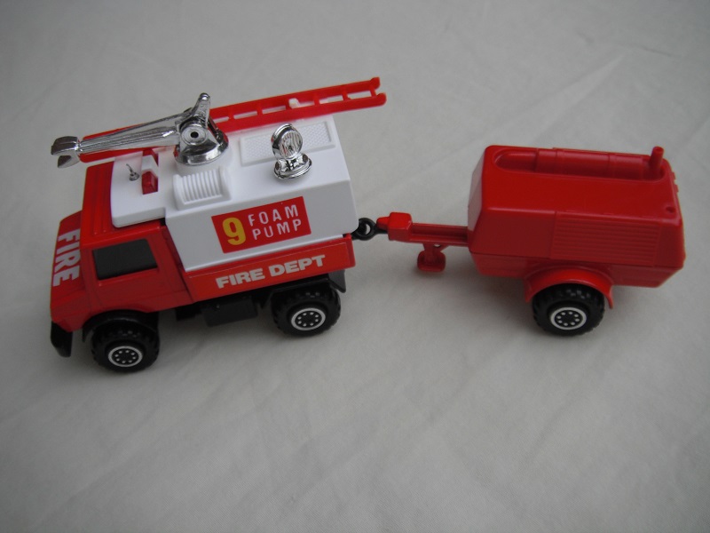 6. Red Unimog/wht canopy/gloss blk base/hole/Macau/clr wind/blk int/red compr/Macau/blk tow eye/Hood lbl typ 3/Foam Pump 9/Fire Dept in cream on red background.