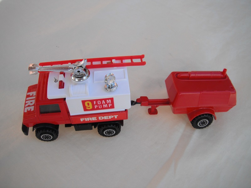 5. Red Unimog/wht canopy/gloss blk base/hole/Macau/clr wind/blk int/red compr/Macau/blk tow eye/Hood lbl typ 3/Foam Pump 9/Fire Dept in white on red background.