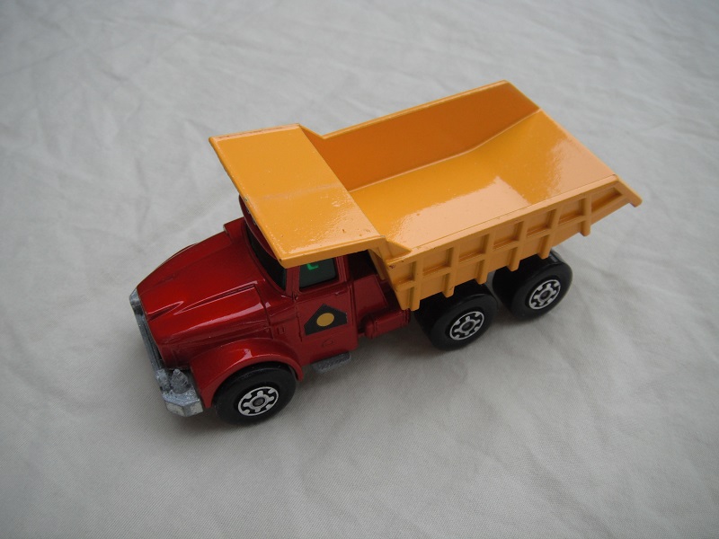 24.Met.red body/blk rad/org-yel tipper/lrg stopper/rear brace/1971 Lesney base/LMC whls/opn lt.tan xle holder/grn wind/yel circle in blk.triangle lbl.