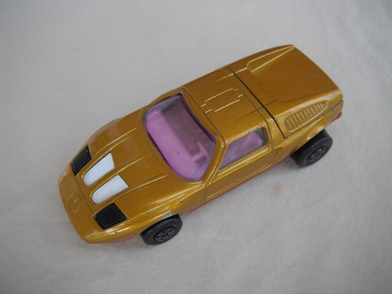 E2. Dk.gold body/met.dk red base/5 spoke wheels/purple windows/wht int/black headlights/w/battery chamber.