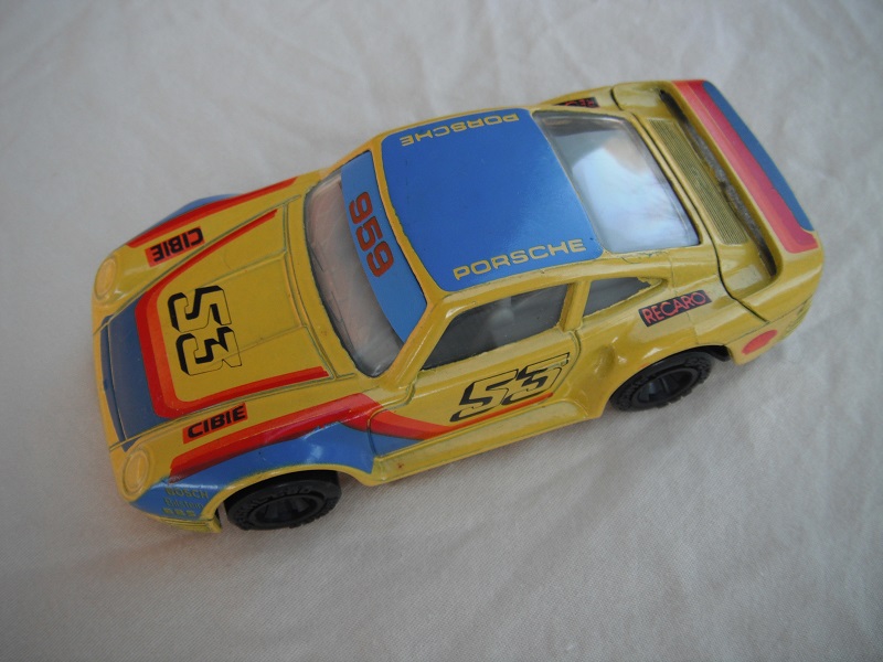 5. Yellow/blue w/red/org stripes/black base China/gray interior/clear windows/unchromed wheels/Porsche #53.