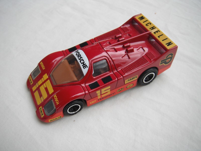 7. Dk.red &amp; orange body/blk base/Macau/clear windows/dk.brown int/unchromed wheels/pullback motor/Michelin Porsche #15.
