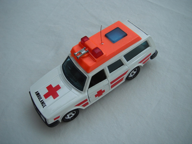 7. White body/orange plastic roof cover/black base/5SMW/dk.blue windows/no trim/tan interior/red dome lts/lrg red cross/stripes.