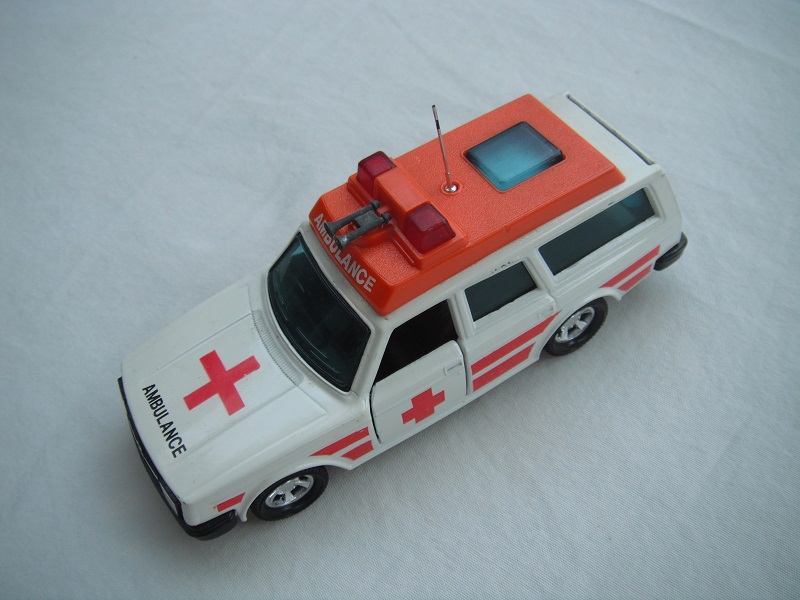 6. White body/orange plastic roof cover/black base/5SMW/dk.blue windows/no trim/tan interior/red dome lts/sml red cross/stripes/ambulance on roof.