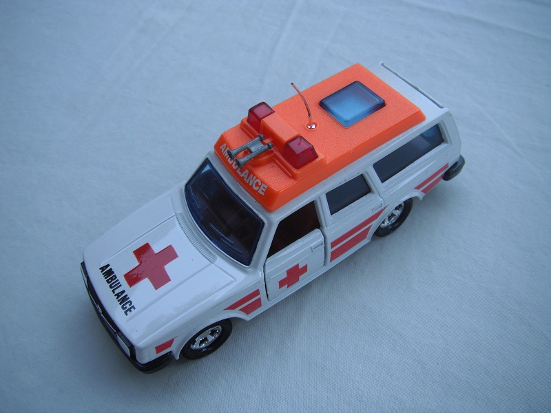 5. White body/orange plastic roof cover/black base/5SMW/blue windows/no trim/orange interior/red dome lts/lrg dk.red cross/stripes/ambulance on roof.