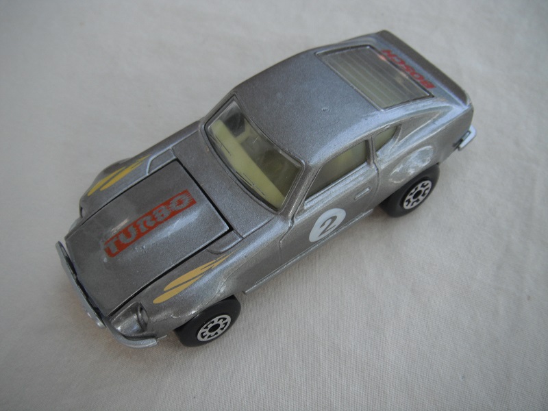 B131. Silver body/silver base/light yellow interior/5 arch front, 5 crown rear wheels/&quot;2&quot; on door &amp; Turbo on hood.