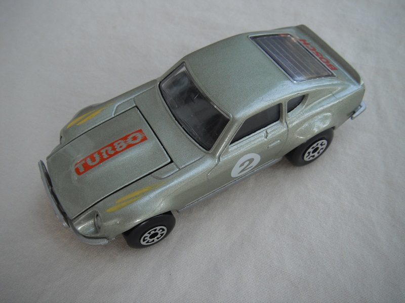 B121. Metallic silver body/silver base/light yellow interior/5 arch front, 5 crown rear wheels/&quot;2&quot; on door &amp; Turbo on hood.