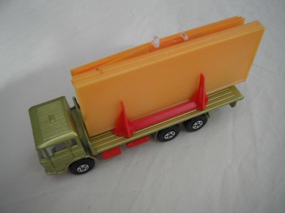 7. Olive green body/dk.red K-13/20 base/clear windows/white int/5 spoke star wheels/white open axle cover/orange building.